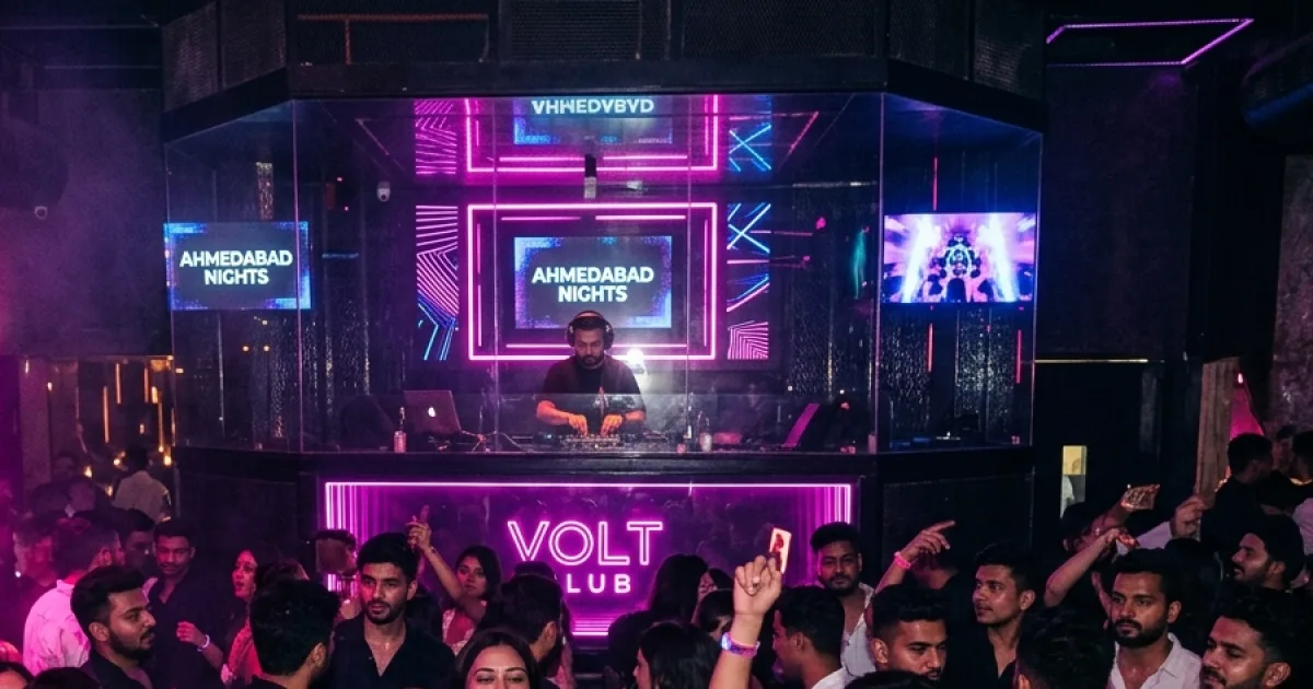 A DJ booth glowing with neon lights above a busy party crowd
